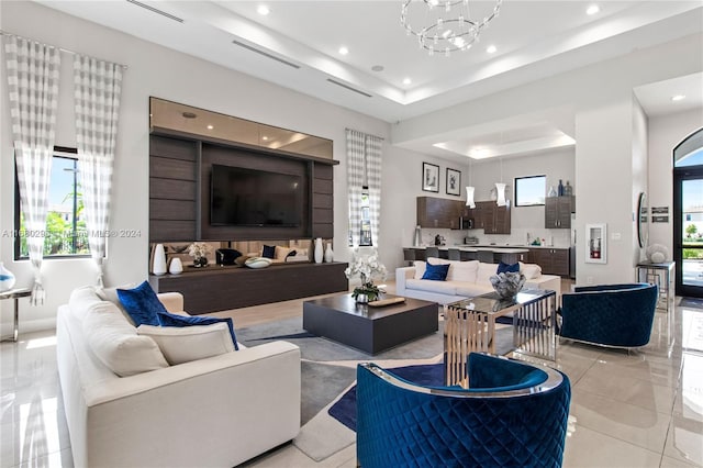 living room with a raised ceiling, plenty of natural light, and a notable chandelier