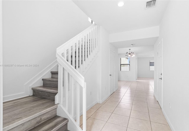 stairs with a chandelier and tile patterned flooring