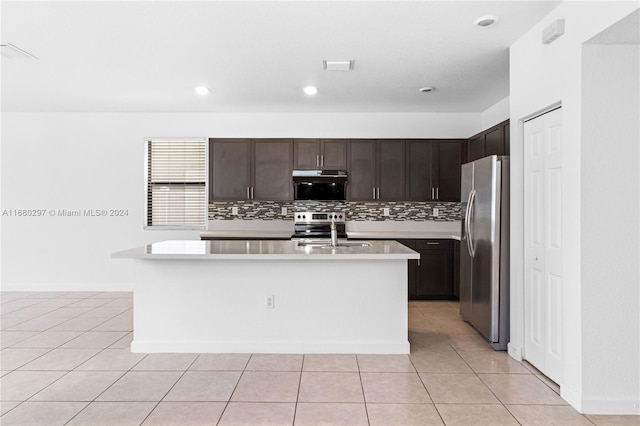 kitchen featuring light tile patterned flooring, appliances with stainless steel finishes, sink, and a center island with sink