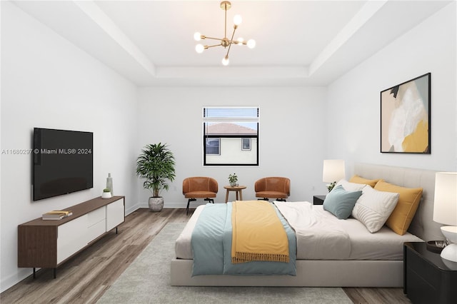 bedroom with a notable chandelier, hardwood / wood-style floors, and a raised ceiling