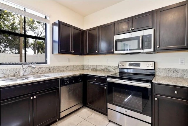 kitchen featuring dark brown cabinetry, light tile patterned floors, appliances with stainless steel finishes, and sink