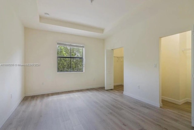 unfurnished room with light hardwood / wood-style flooring and a raised ceiling