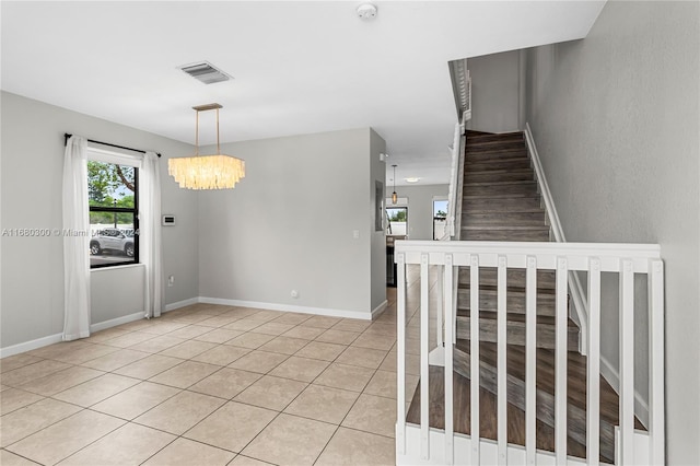 staircase featuring tile patterned floors and an inviting chandelier