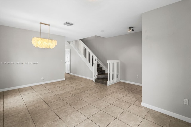 tiled empty room featuring an inviting chandelier