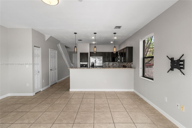 kitchen featuring stainless steel refrigerator with ice dispenser, kitchen peninsula, backsplash, light tile patterned flooring, and light stone counters