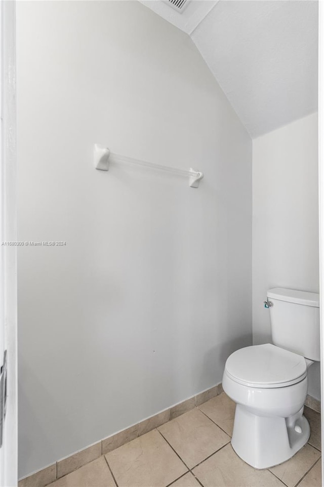 bathroom with lofted ceiling, toilet, and tile patterned floors