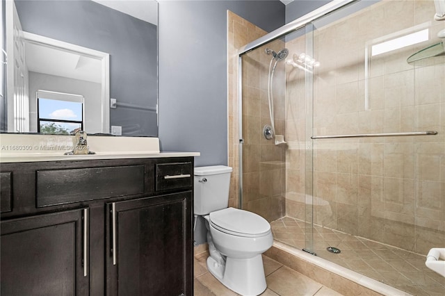 bathroom featuring vanity, toilet, tile patterned floors, and a shower with shower door