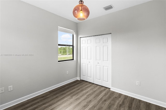 unfurnished bedroom featuring dark wood-type flooring and a closet