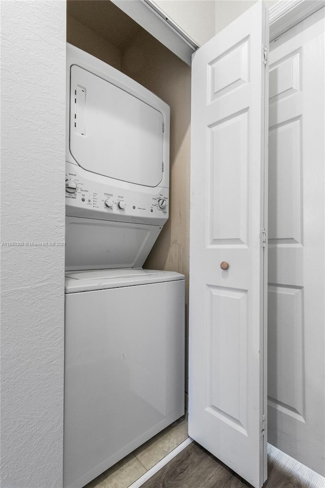 laundry room featuring stacked washer and clothes dryer and dark hardwood / wood-style flooring