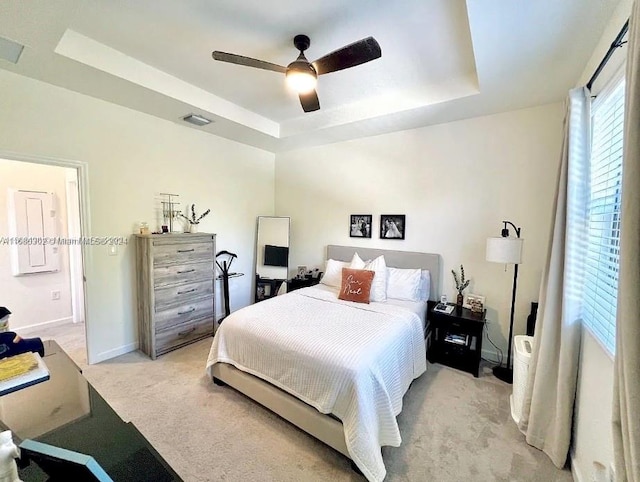 carpeted bedroom with a tray ceiling and ceiling fan