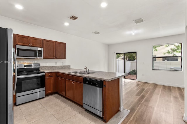 kitchen featuring sink, appliances with stainless steel finishes, kitchen peninsula, and light wood-type flooring