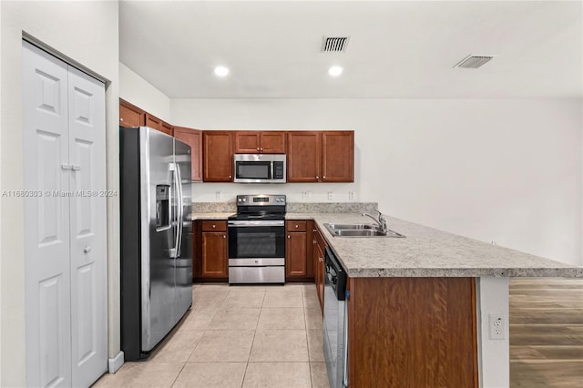 kitchen with light tile patterned floors, appliances with stainless steel finishes, sink, and a kitchen breakfast bar