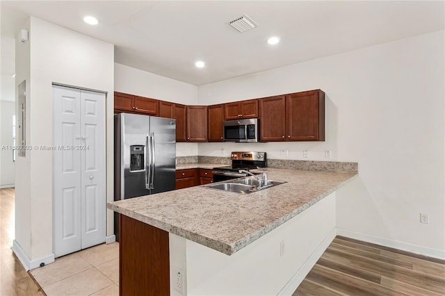 kitchen featuring sink, appliances with stainless steel finishes, light hardwood / wood-style flooring, and kitchen peninsula