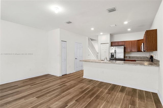 kitchen with dark hardwood / wood-style floors, kitchen peninsula, sink, appliances with stainless steel finishes, and light stone counters