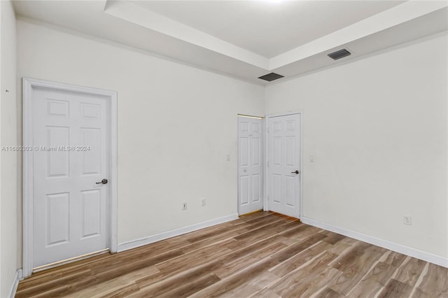 spare room featuring a tray ceiling and hardwood / wood-style floors