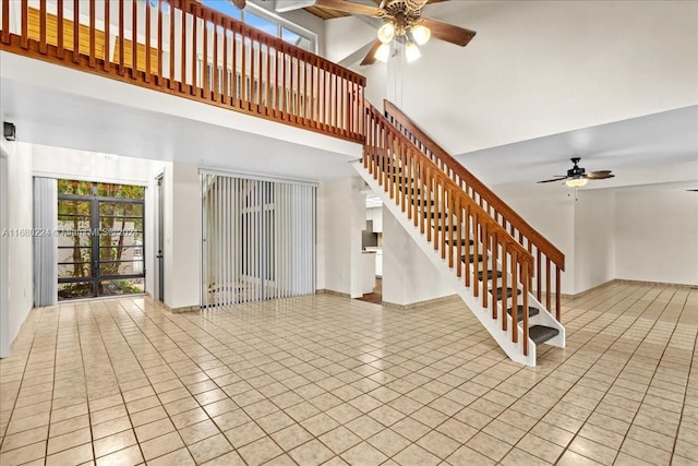 unfurnished living room with a high ceiling, ceiling fan, and light tile patterned flooring