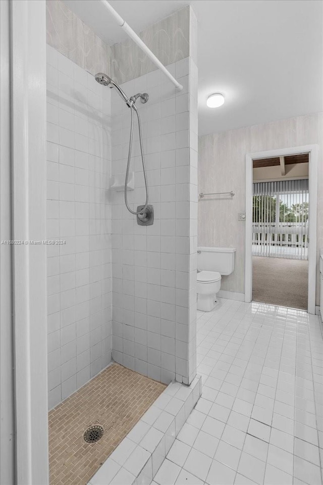 bathroom featuring tiled shower, tile patterned flooring, and toilet