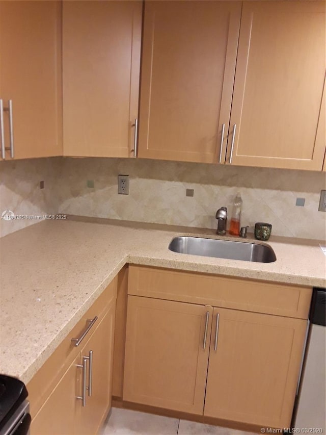 kitchen featuring decorative backsplash, light stone countertops, dishwashing machine, and sink