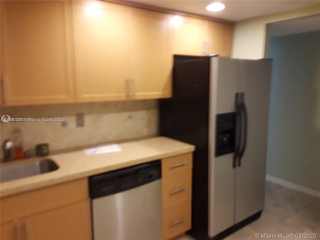 kitchen with sink, tasteful backsplash, light tile patterned floors, light brown cabinetry, and appliances with stainless steel finishes