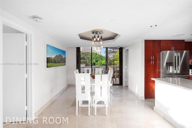 unfurnished dining area featuring an inviting chandelier, a wall of windows, and a tray ceiling