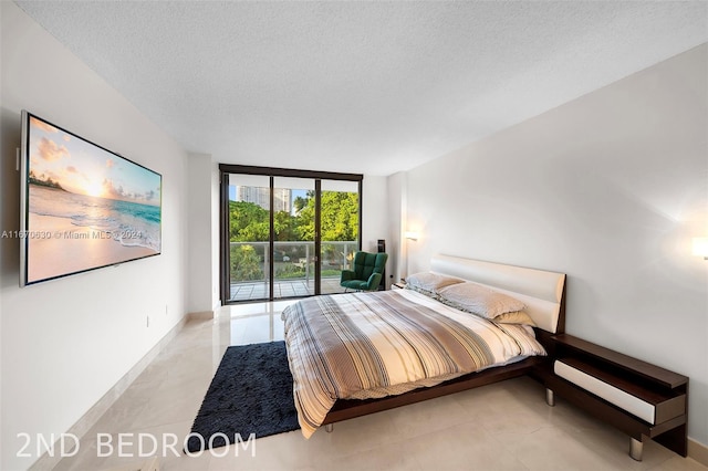 bedroom with a textured ceiling, access to outside, and a wall of windows