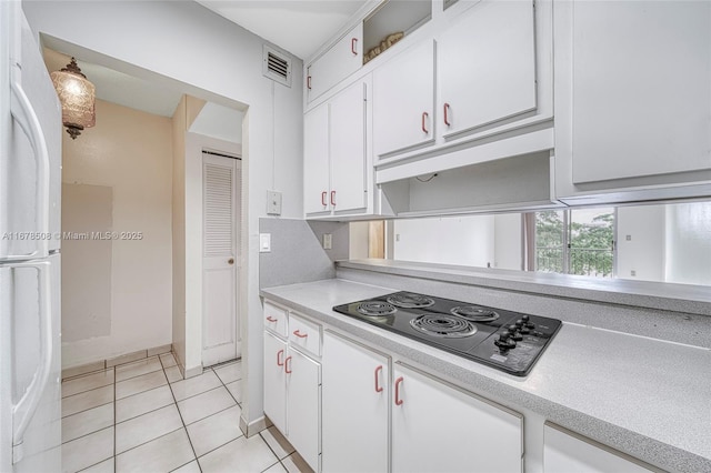 kitchen featuring white refrigerator, white cabinets, light tile patterned floors, and black electric cooktop