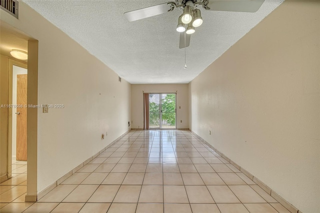 empty room featuring a textured ceiling, ceiling fan, and light tile patterned floors