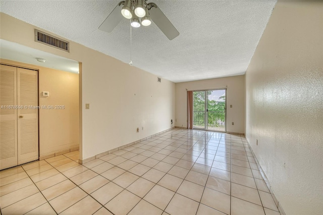 tiled spare room with ceiling fan and a textured ceiling