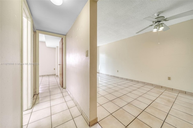 corridor with light tile patterned flooring, a textured ceiling, and vaulted ceiling