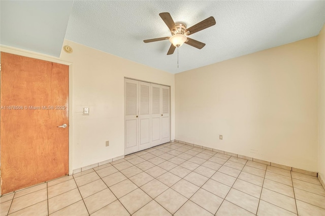 unfurnished bedroom featuring light tile patterned floors, a closet, ceiling fan, and a textured ceiling