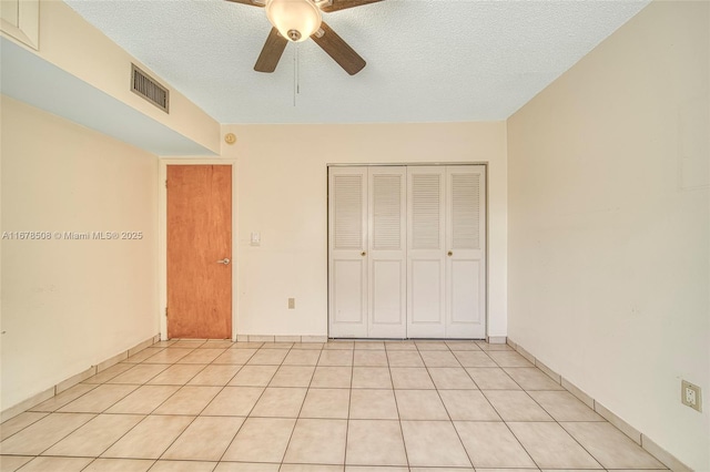 unfurnished bedroom featuring light tile patterned flooring, a closet, ceiling fan, and a textured ceiling