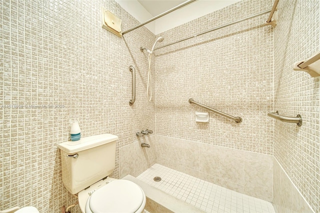 bathroom with a tile shower and toilet