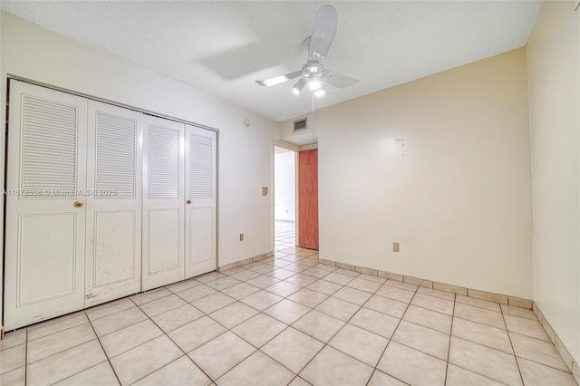 unfurnished bedroom featuring a textured ceiling, light tile patterned flooring, ceiling fan, and a closet