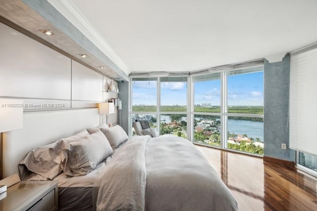 bedroom with floor to ceiling windows, hardwood / wood-style floors, a water view, and ornamental molding