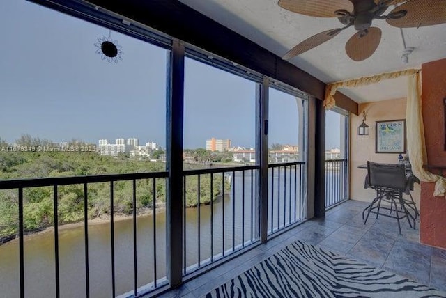 sunroom / solarium featuring a water view and ceiling fan