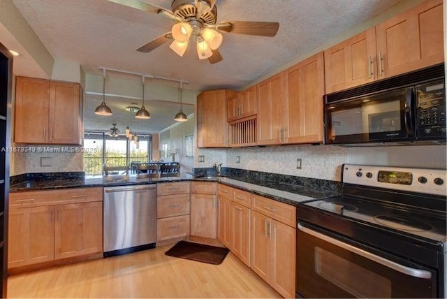 kitchen featuring a textured ceiling, light hardwood / wood-style flooring, appliances with stainless steel finishes, dark stone counters, and backsplash