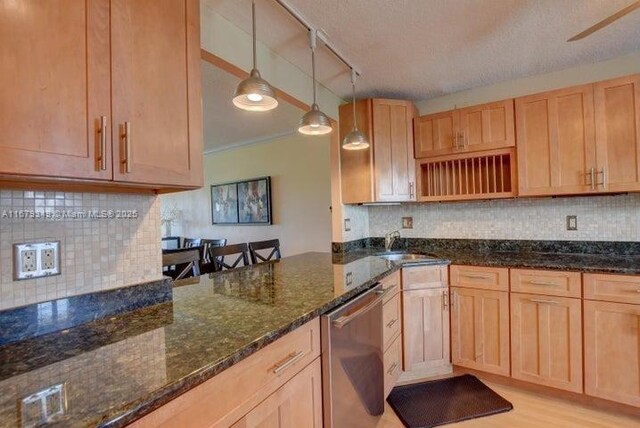 kitchen with hanging light fixtures, sink, dark stone counters, and dishwasher