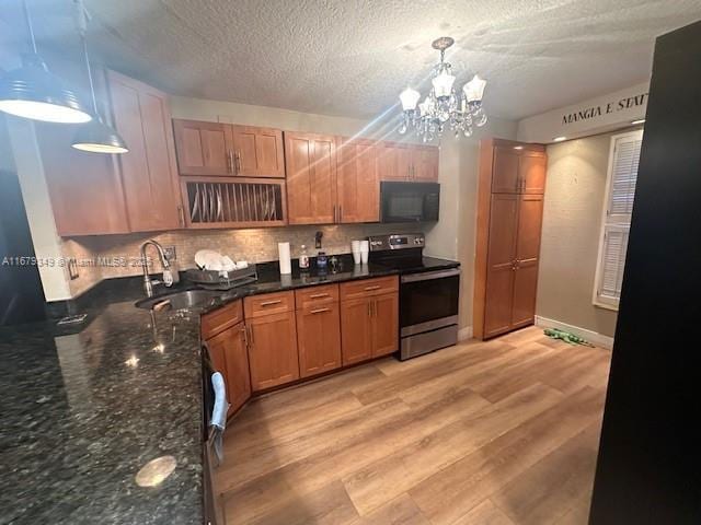 kitchen featuring electric stove, decorative light fixtures, sink, decorative backsplash, and light hardwood / wood-style flooring