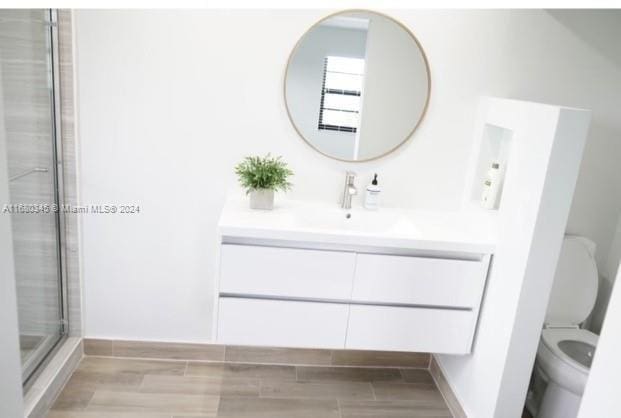 bathroom with vanity, toilet, hardwood / wood-style flooring, and an enclosed shower