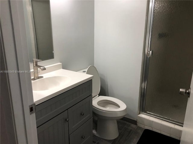 bathroom featuring a shower with door, toilet, and vanity