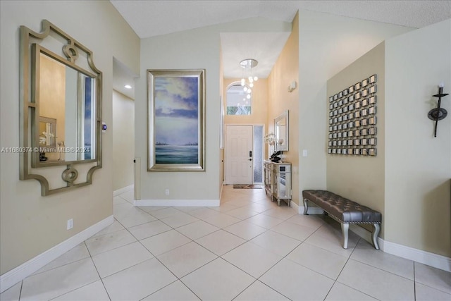 hallway with a textured ceiling, light tile patterned floors, a chandelier, and vaulted ceiling