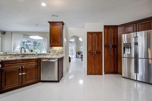 kitchen with sink, appliances with stainless steel finishes, light stone countertops, light tile patterned floors, and hanging light fixtures