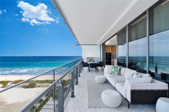 balcony featuring an outdoor hangout area, a water view, and a view of the beach