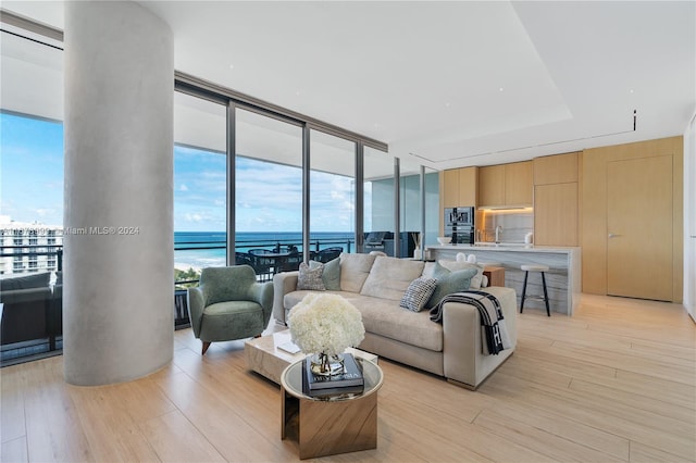 living room with expansive windows, light hardwood / wood-style flooring, and a water view