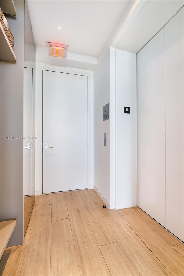 hall with light wood-type flooring and elevator