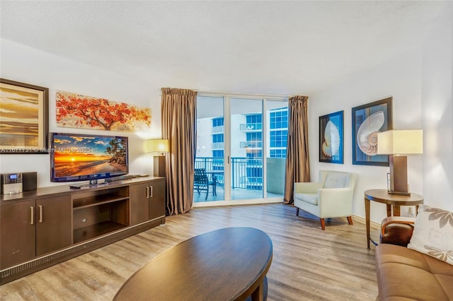 living area featuring light wood-type flooring, floor to ceiling windows, a textured ceiling, and baseboards