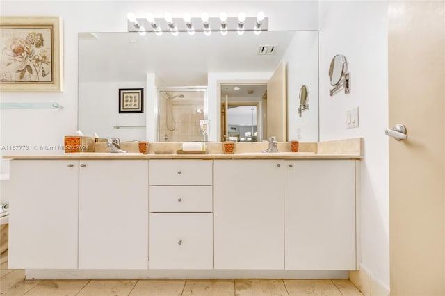 bathroom with double vanity, a shower stall, visible vents, and a sink