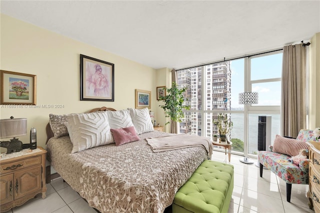 bedroom featuring a water view, expansive windows, multiple windows, and light tile patterned floors