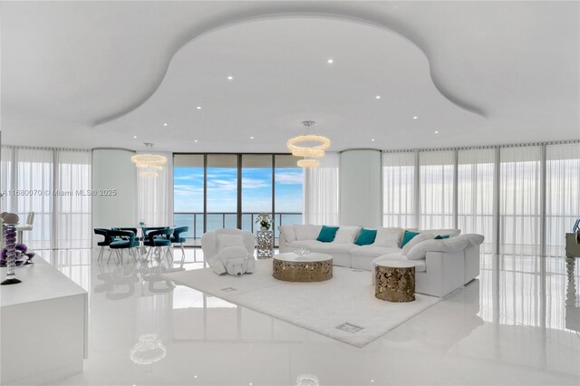 living room featuring a water view, tile patterned floors, a chandelier, and a wall of windows