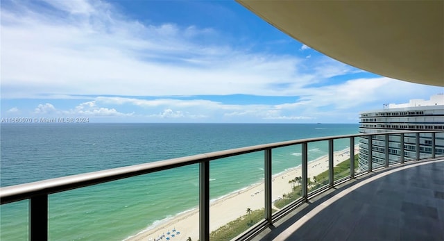 balcony with a water view and a view of the beach